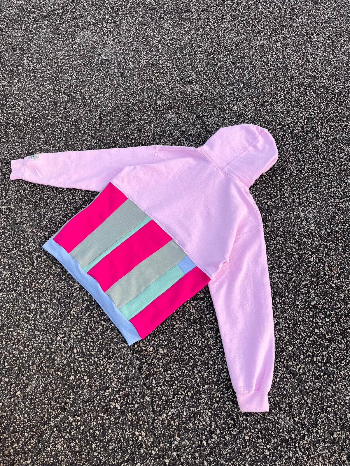 A pink and blue striped hoodie laying on the ground.