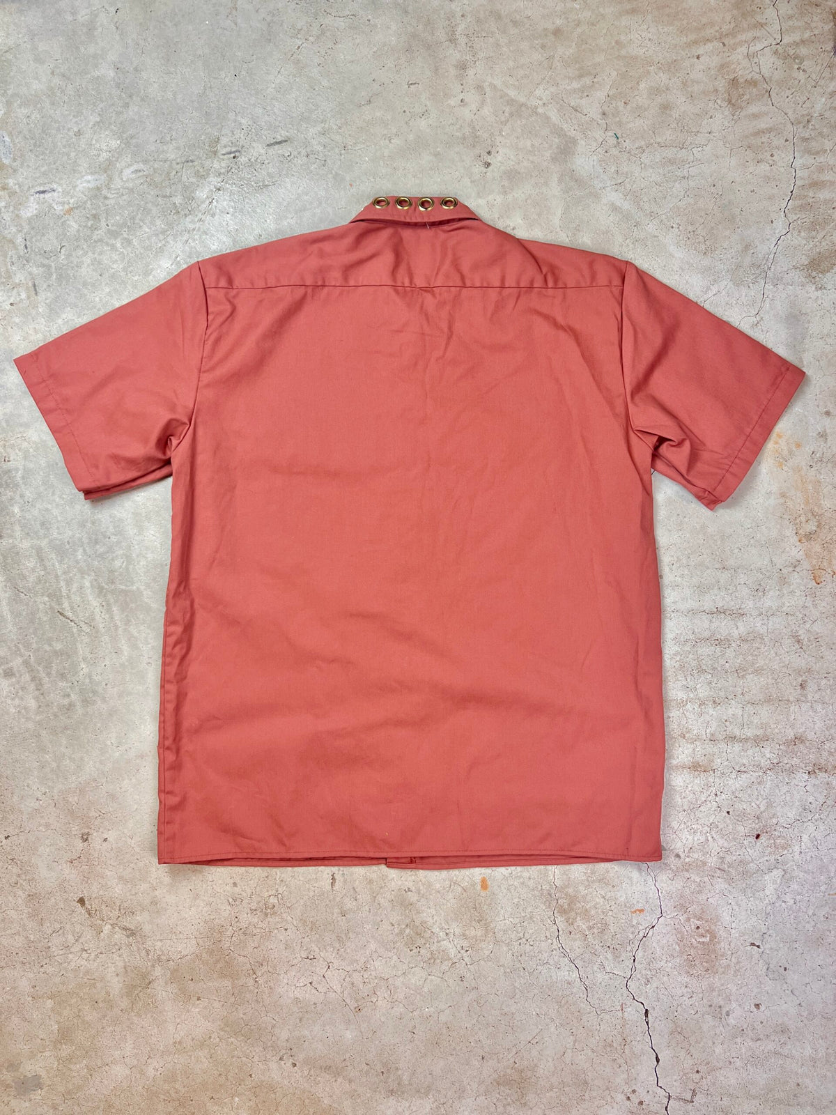 The back of a red shirt on a concrete floor.