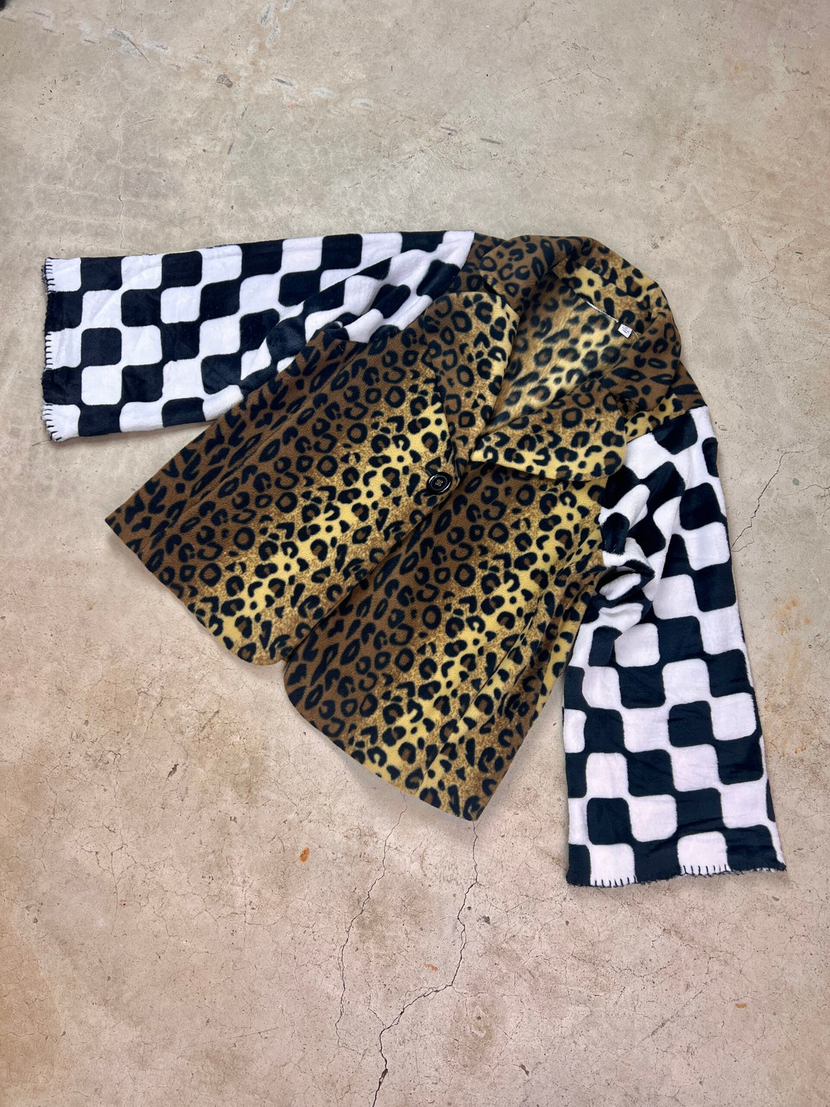 A cheetah print coat on a concrete surface.