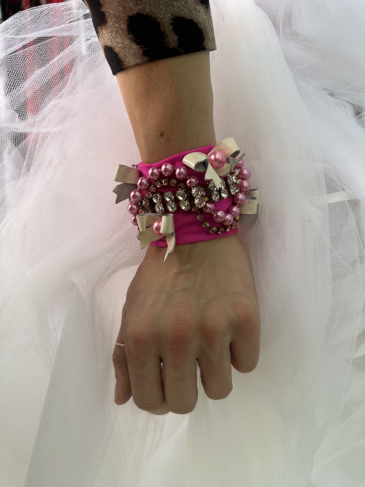 A woman wearing a pink bracelet with pearls on it.