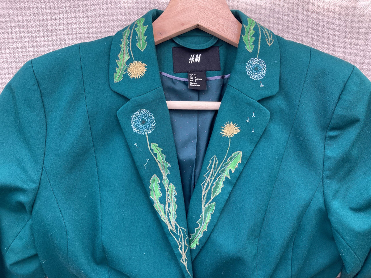 A teal jacket with hand-painted flowers on it.