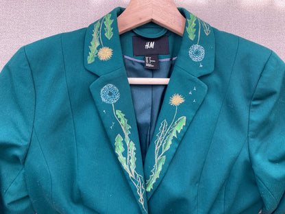 A teal jacket with hand-painted flowers on it.