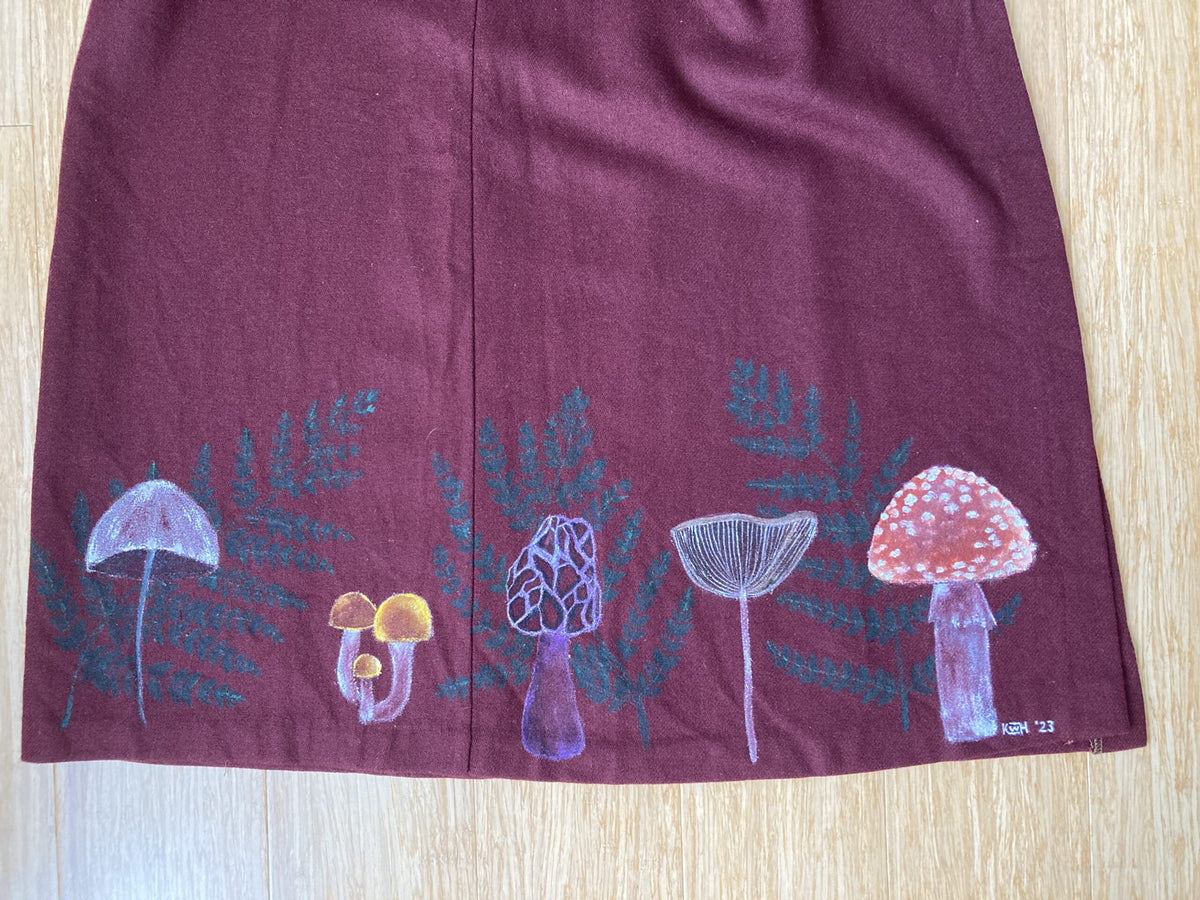 A maroon skirt with mushrooms and ferns on it.