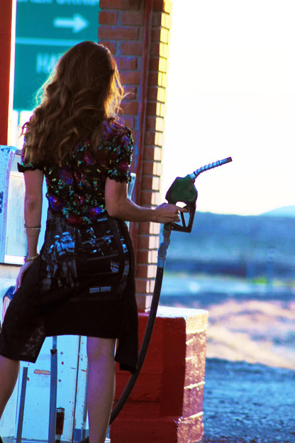 a woman pumping gas into her car at a gas station.