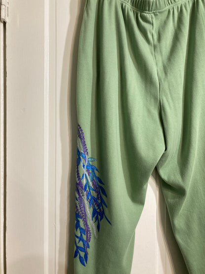 A pair of hand-painted green sweatpants hanging on a door.