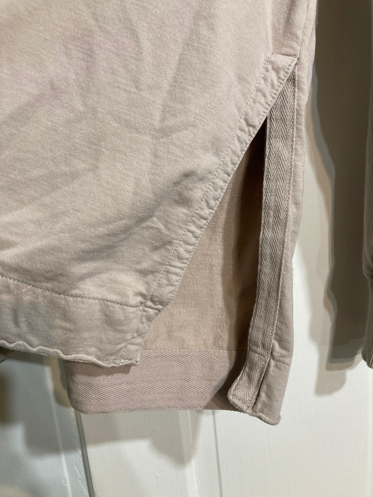 A close up of a beige hoodie hanging on a door.