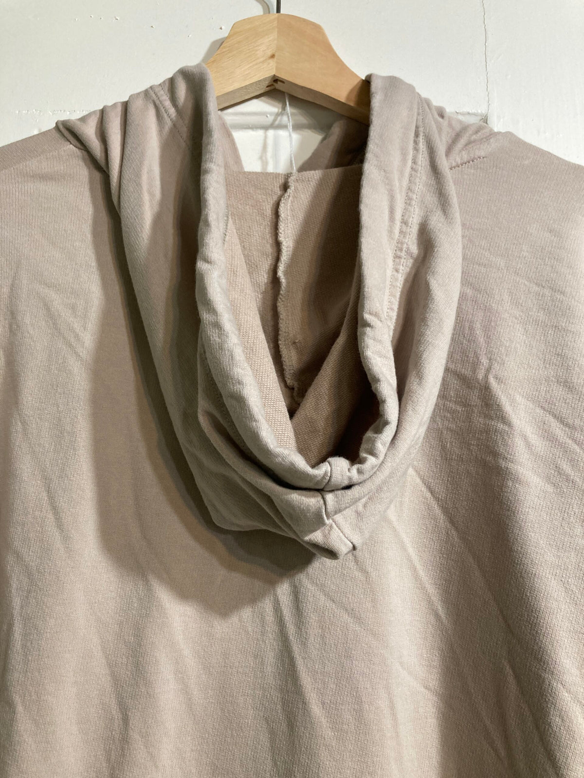 A beige hoodie hanging on a hanger.