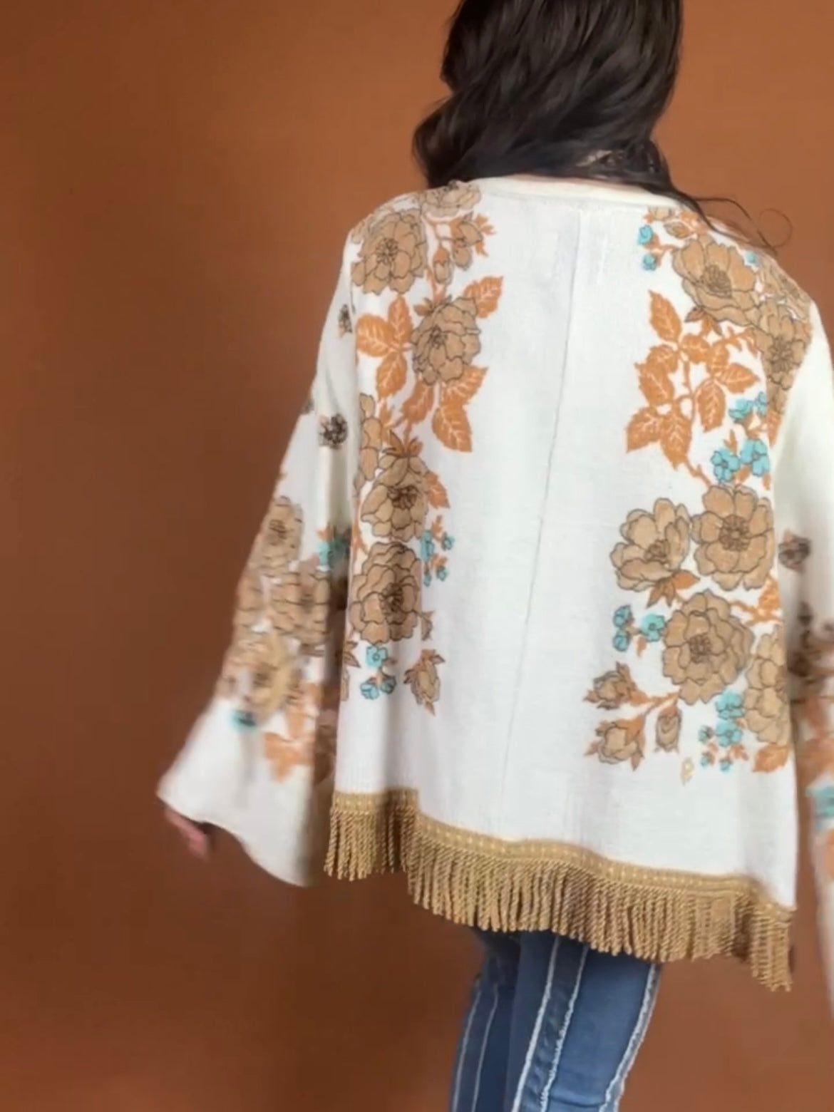 The back of a woman wearing a fringed jacket.