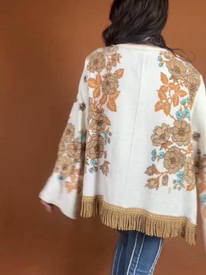 The back of a woman wearing a fringed jacket.