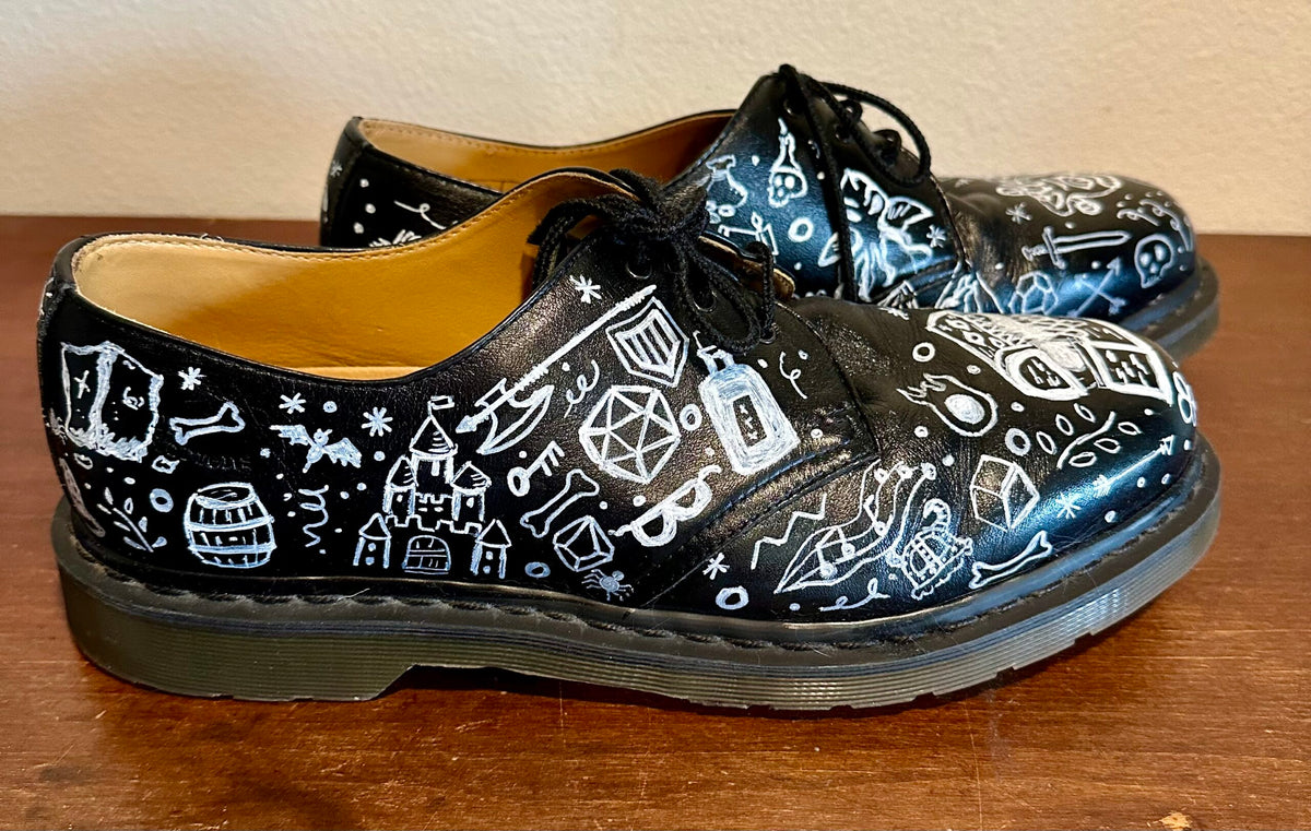 A pair of black shoes with white drawings on them.