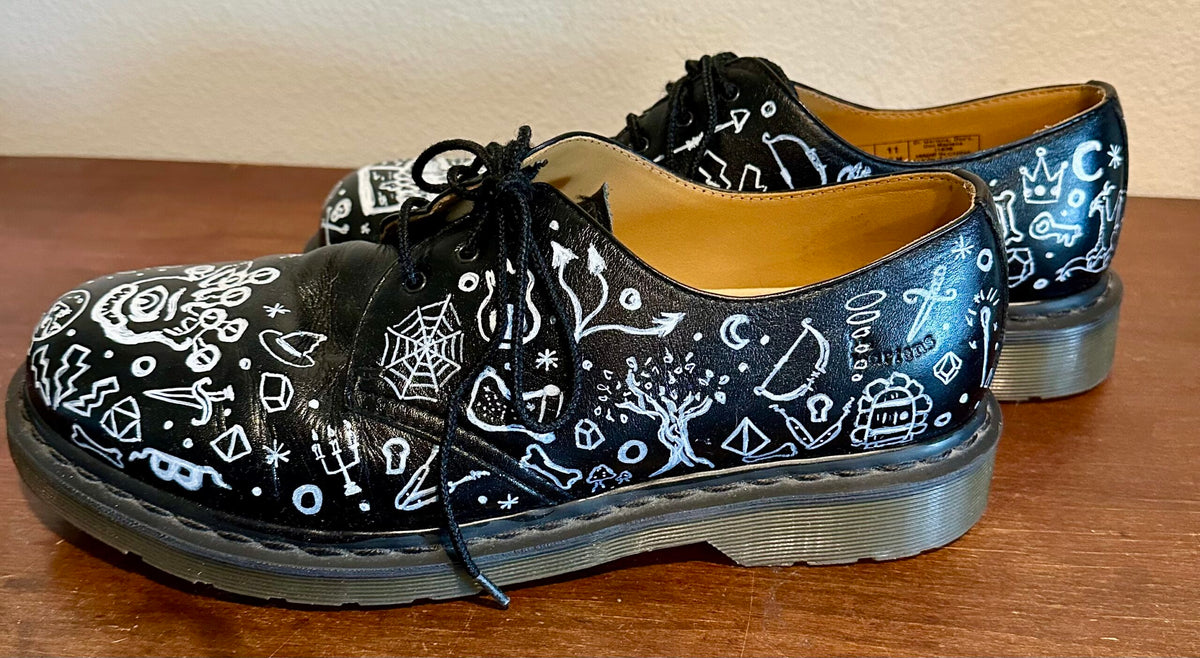 A pair of black shoes with white drawings on them.
