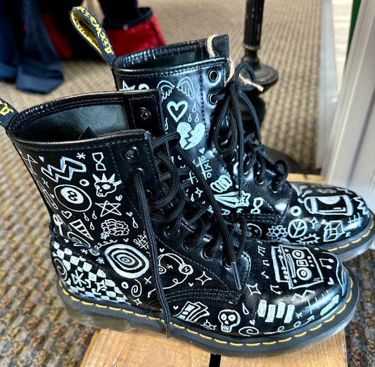 A pair of black boots with white drawings on them.