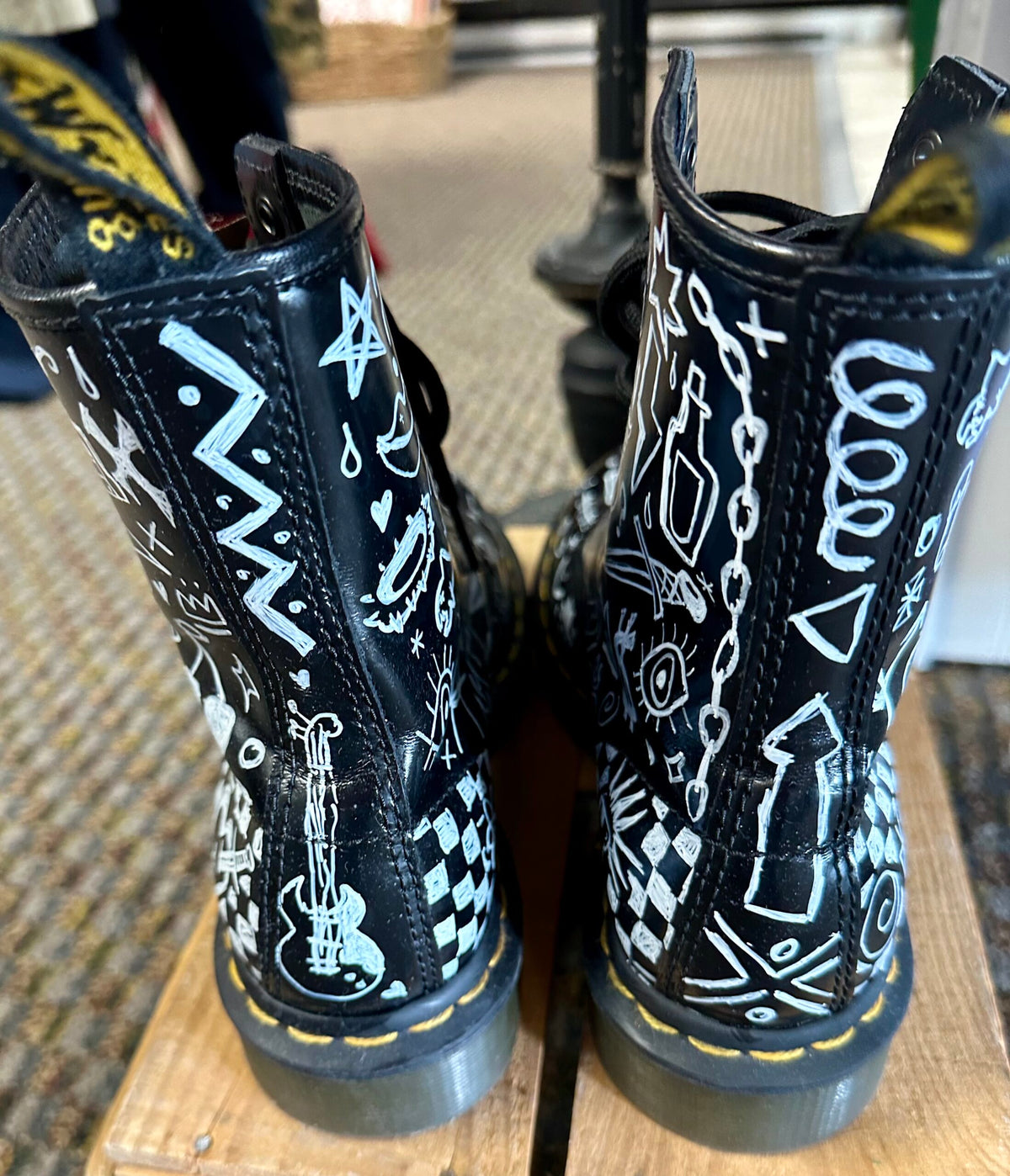 A pair of black dr martens boots with doodles on them.