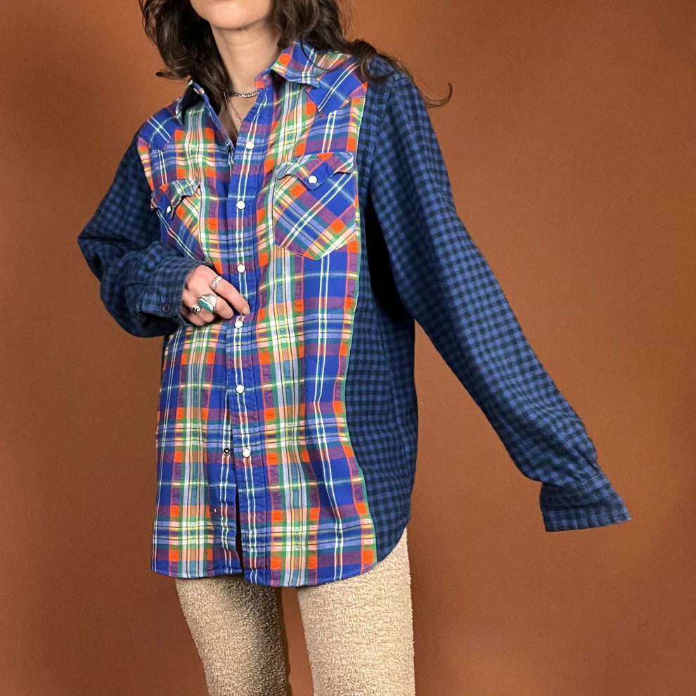 A woman in The Plaid Flannel Mash Up Button Down Shirt In Blue/Orange poses for a picture.