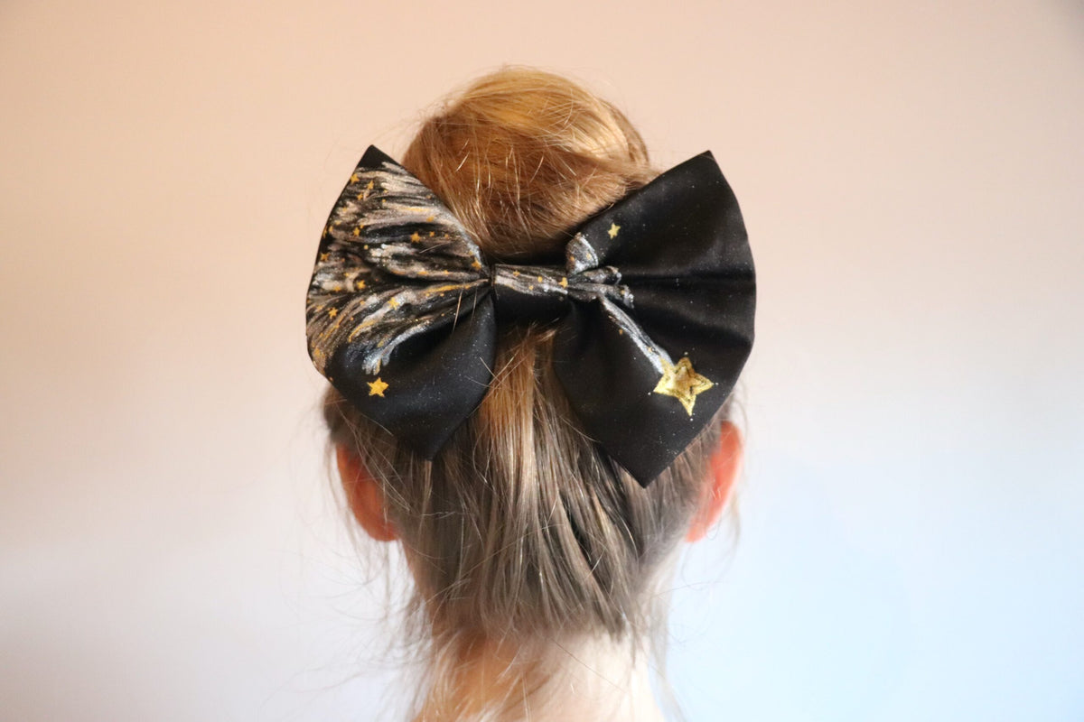 Woman wearing a large hand-painted black bow with stars