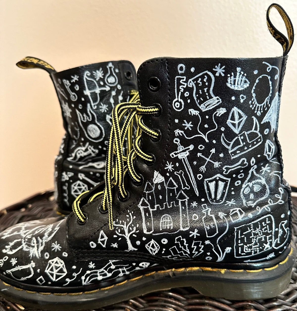 A pair of black boots with white drawings on them.