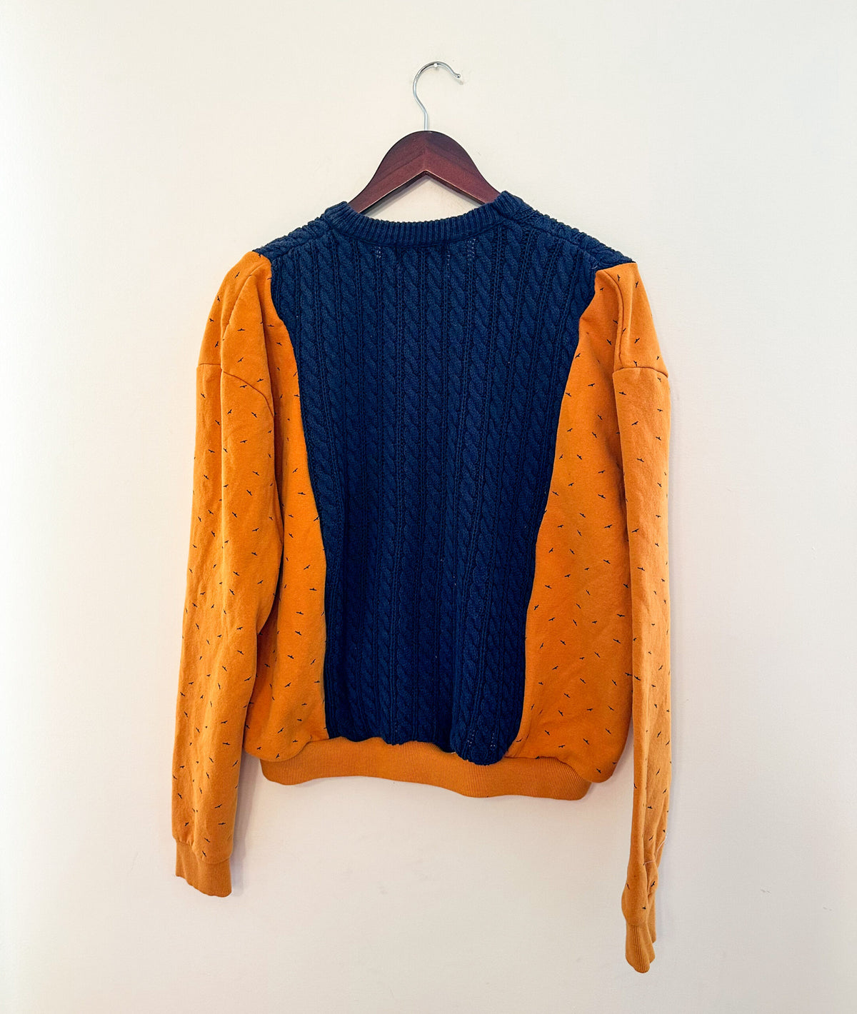 An orange and blue sweater hanging on a wall.
