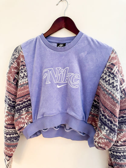 A purple nike cropped sweater hanging on a hanger.