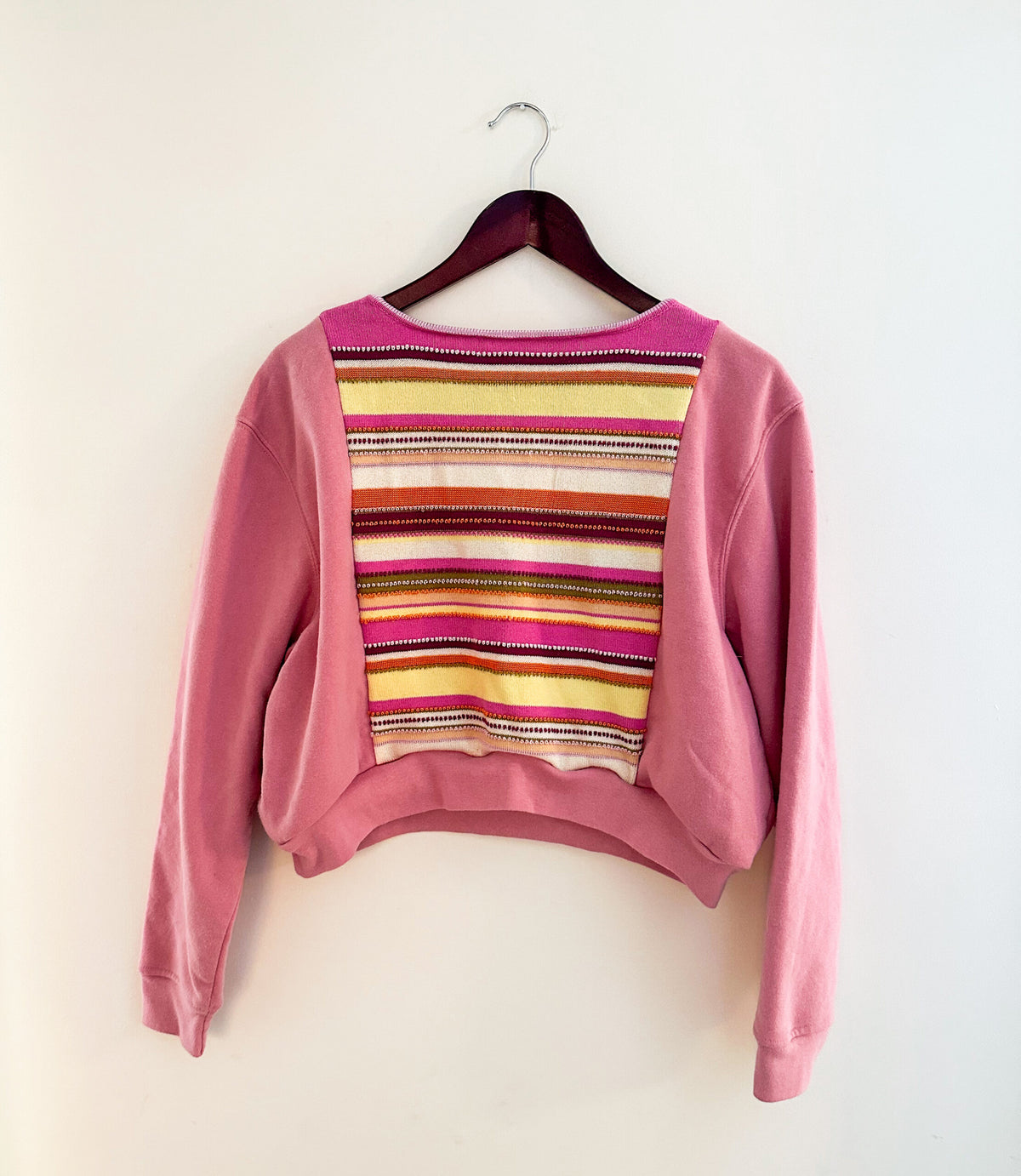 A pink striped sweater hanging on a wall.