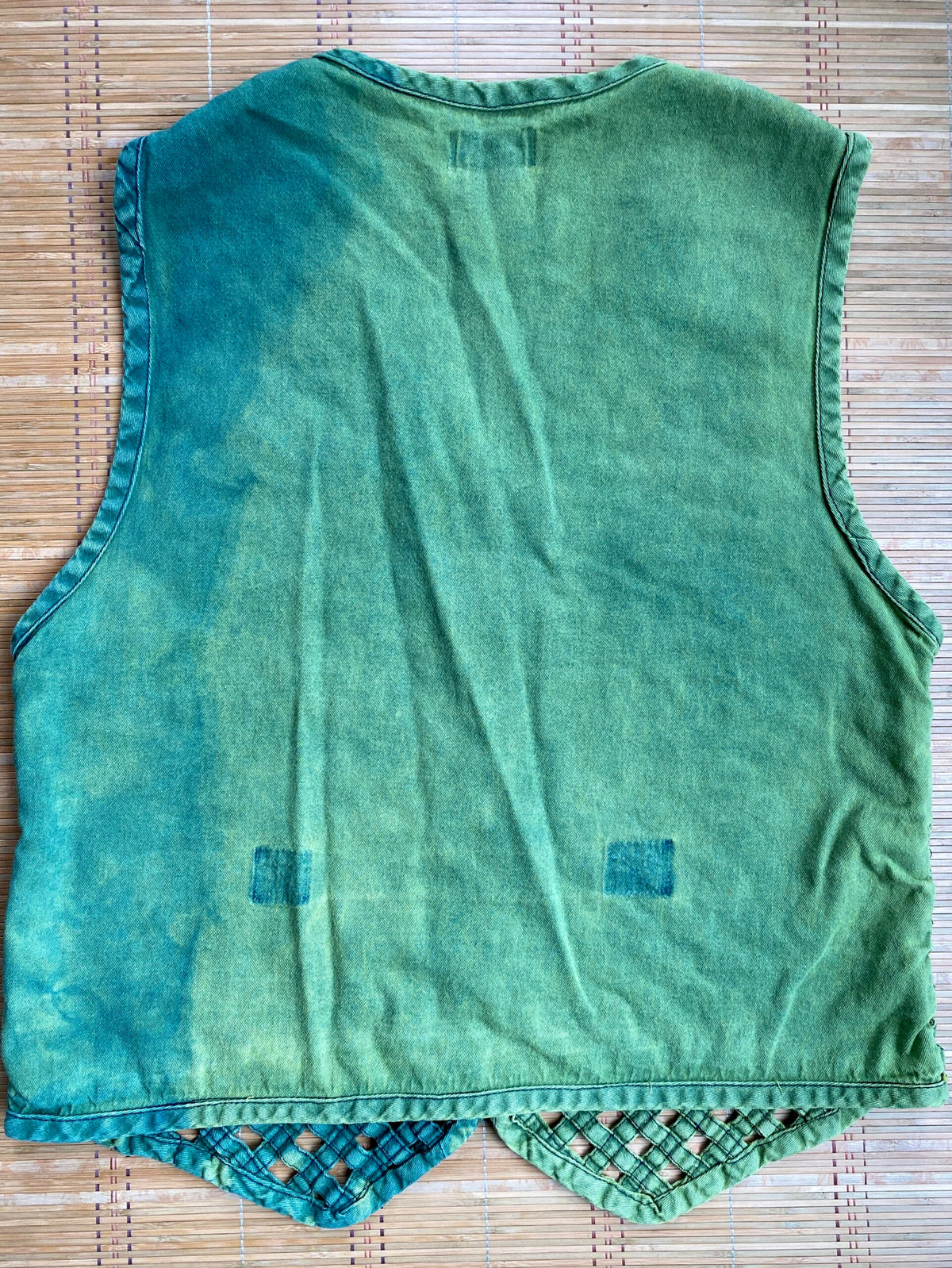 A green vest on a bamboo mat.