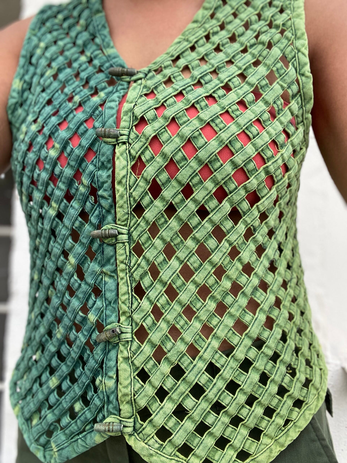 A woman wearing a green woven vest.