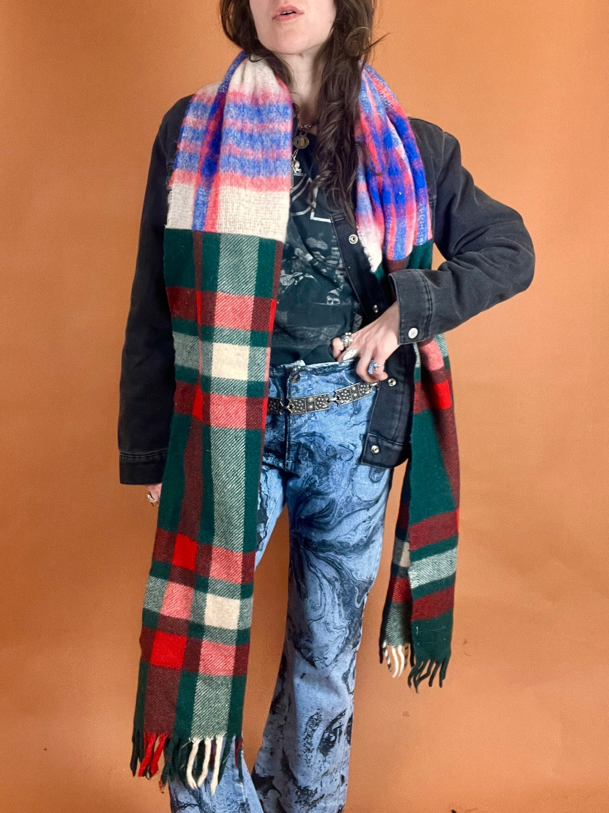 A woman wearing a plaid scarf and jeans.