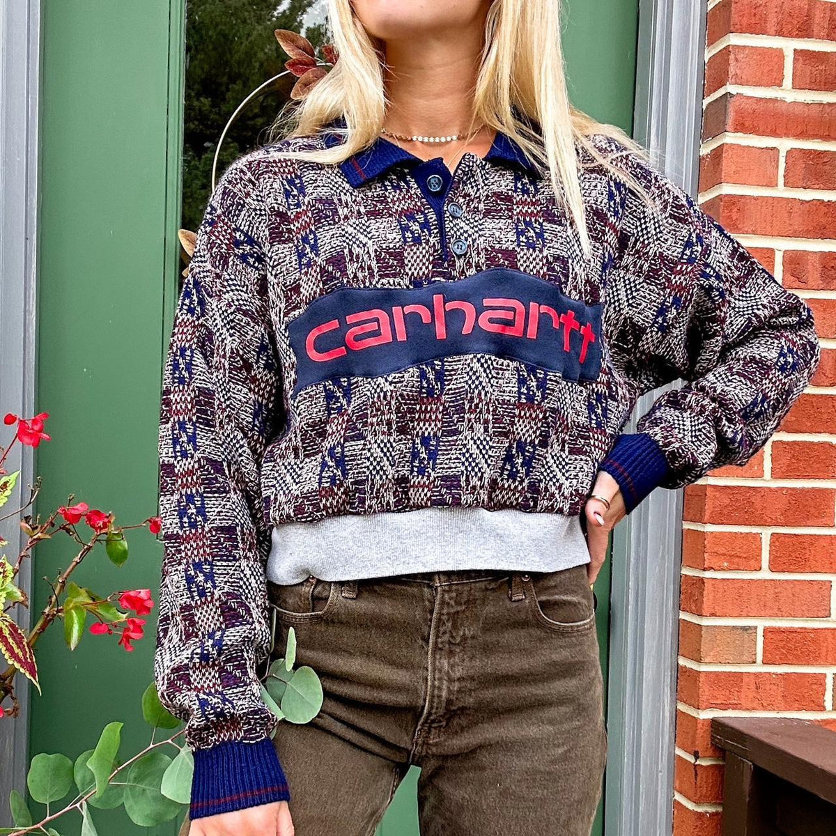 A woman is standing outside wearing a sweater and jeans.