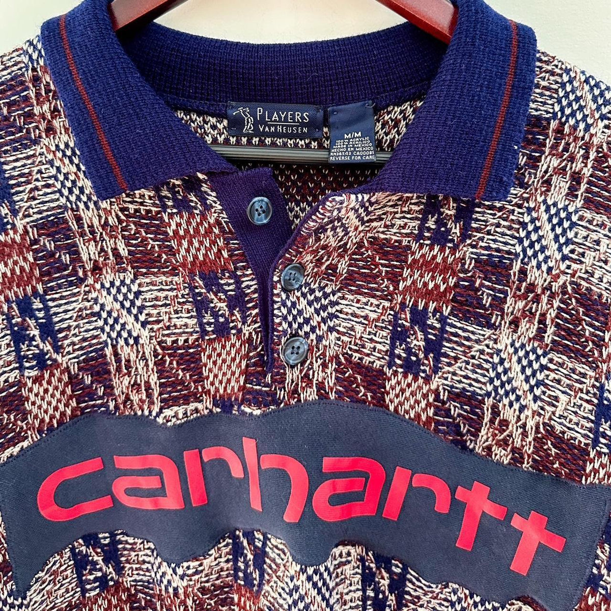A carhartt polo shirt hanging on a hanger.