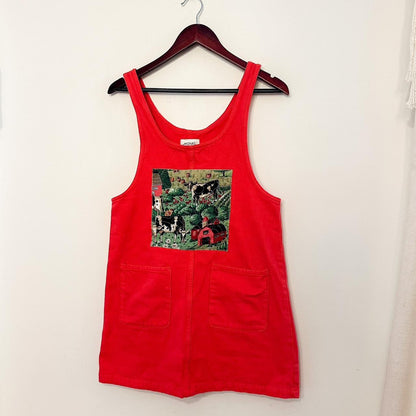 A red dress hangs on a hanger with a picture on it.