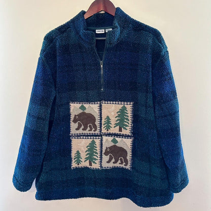 A blue sweater with bears and trees on it.