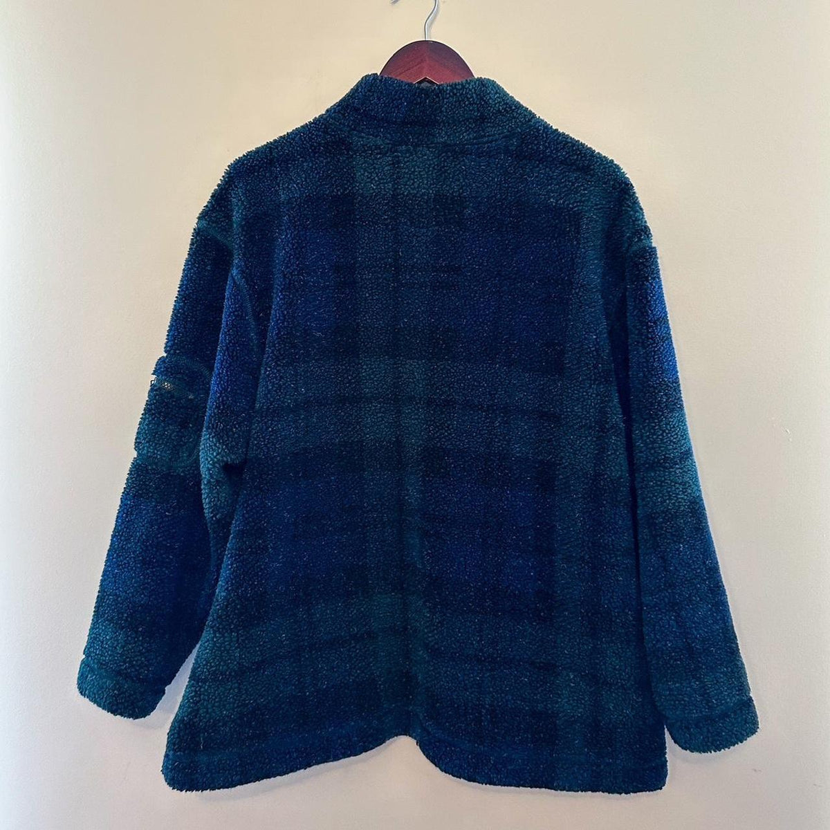 A blue and green plaid jacket hanging on a hanger.