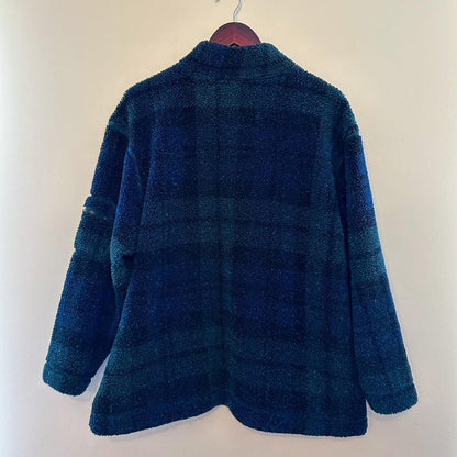 A blue and green plaid jacket hanging on a hanger.