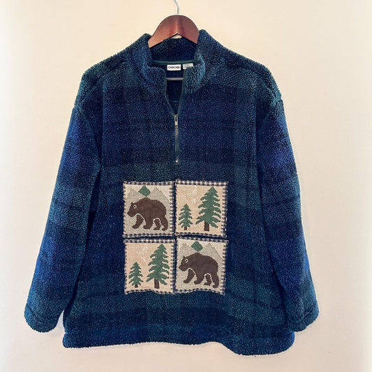A blue sweater with bears and trees on it.