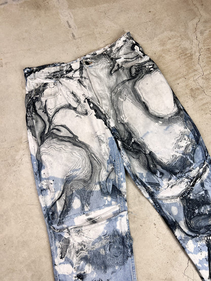 A pair of jeans with black and white paint on them.