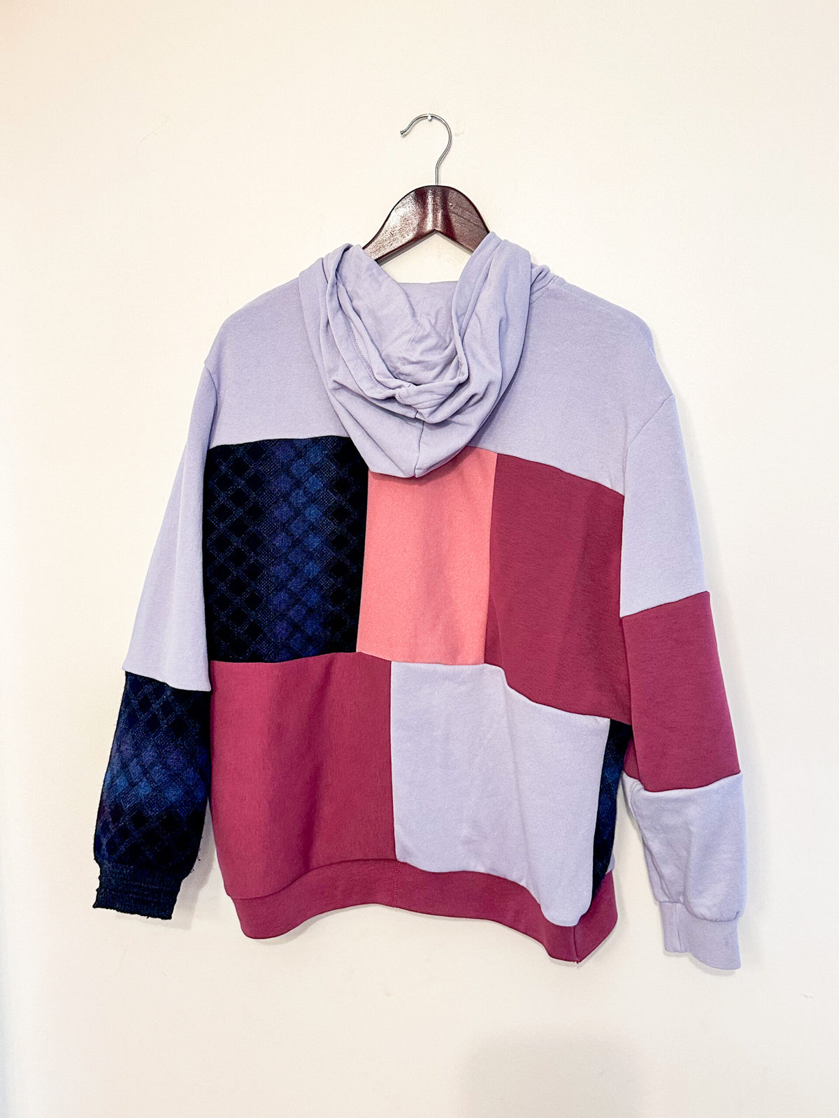 A purple, pink, and blue hoodie hanging on a wall.