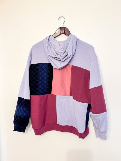 A purple, pink, and blue hoodie hanging on a wall.