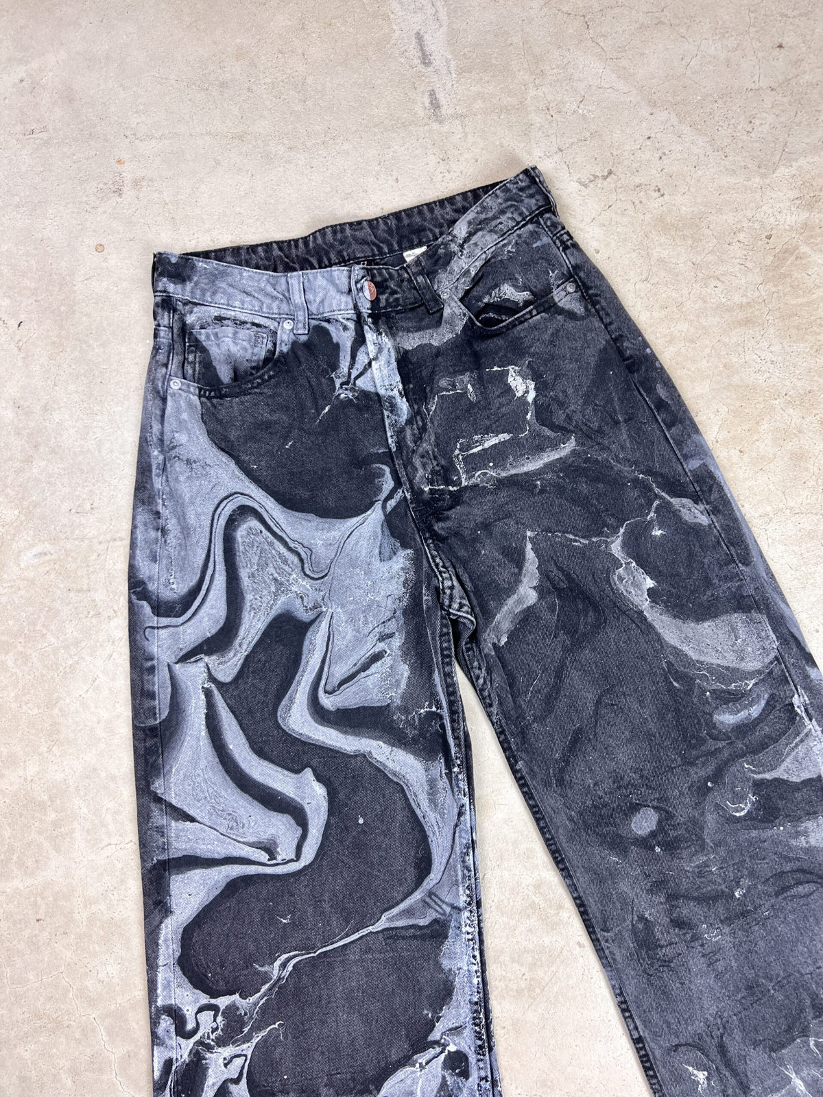 A pair of black and white marbled jeans.