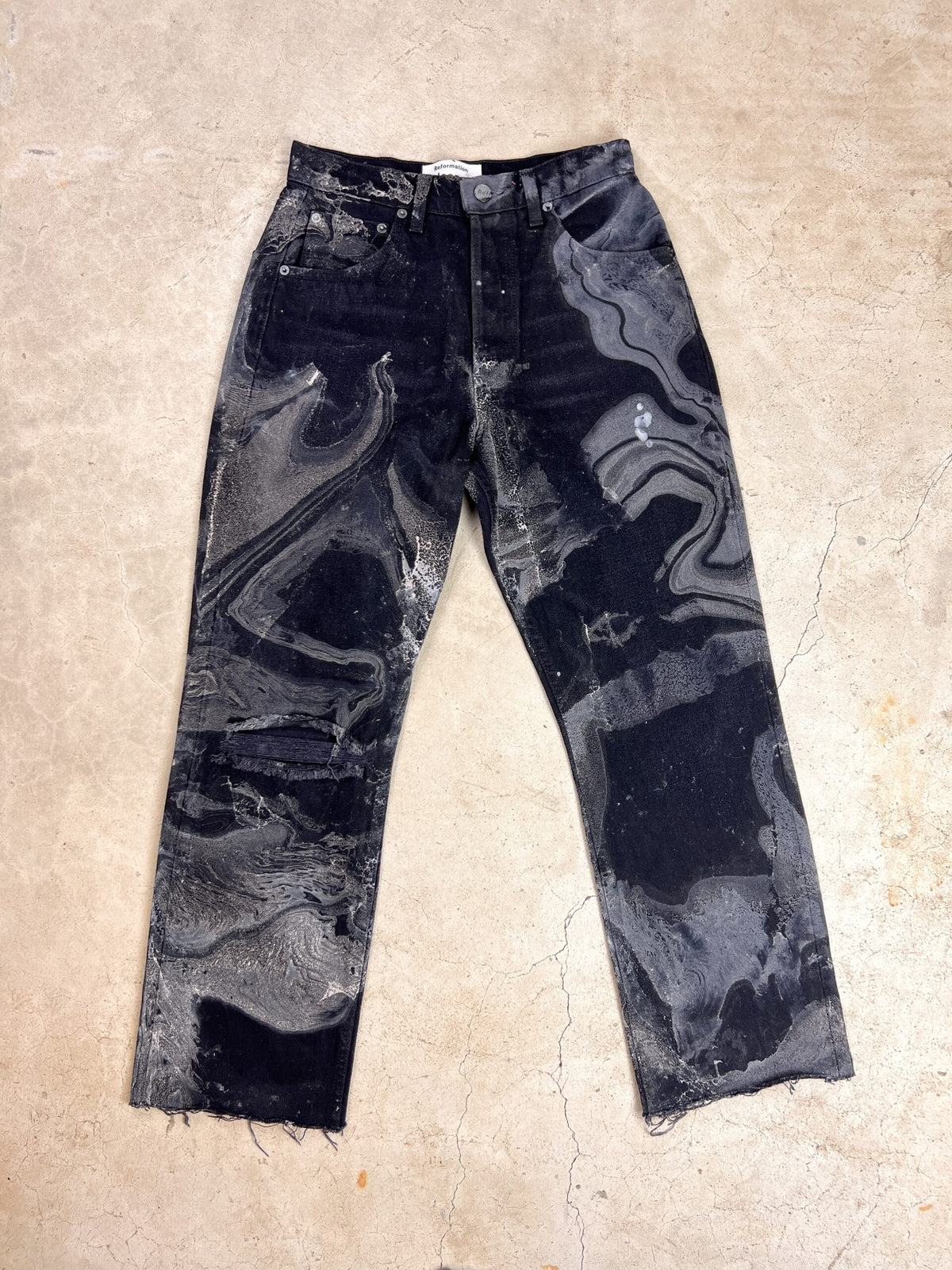 A pair of black jeans with stains on them.