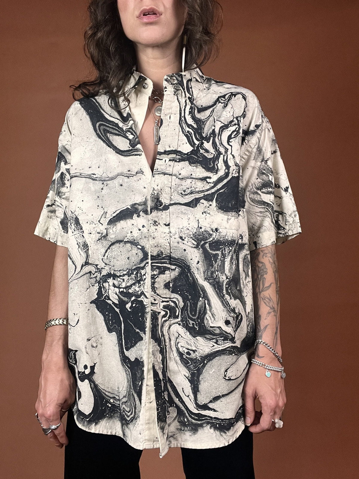 A woman wearing a shirt with a black and white marble print.