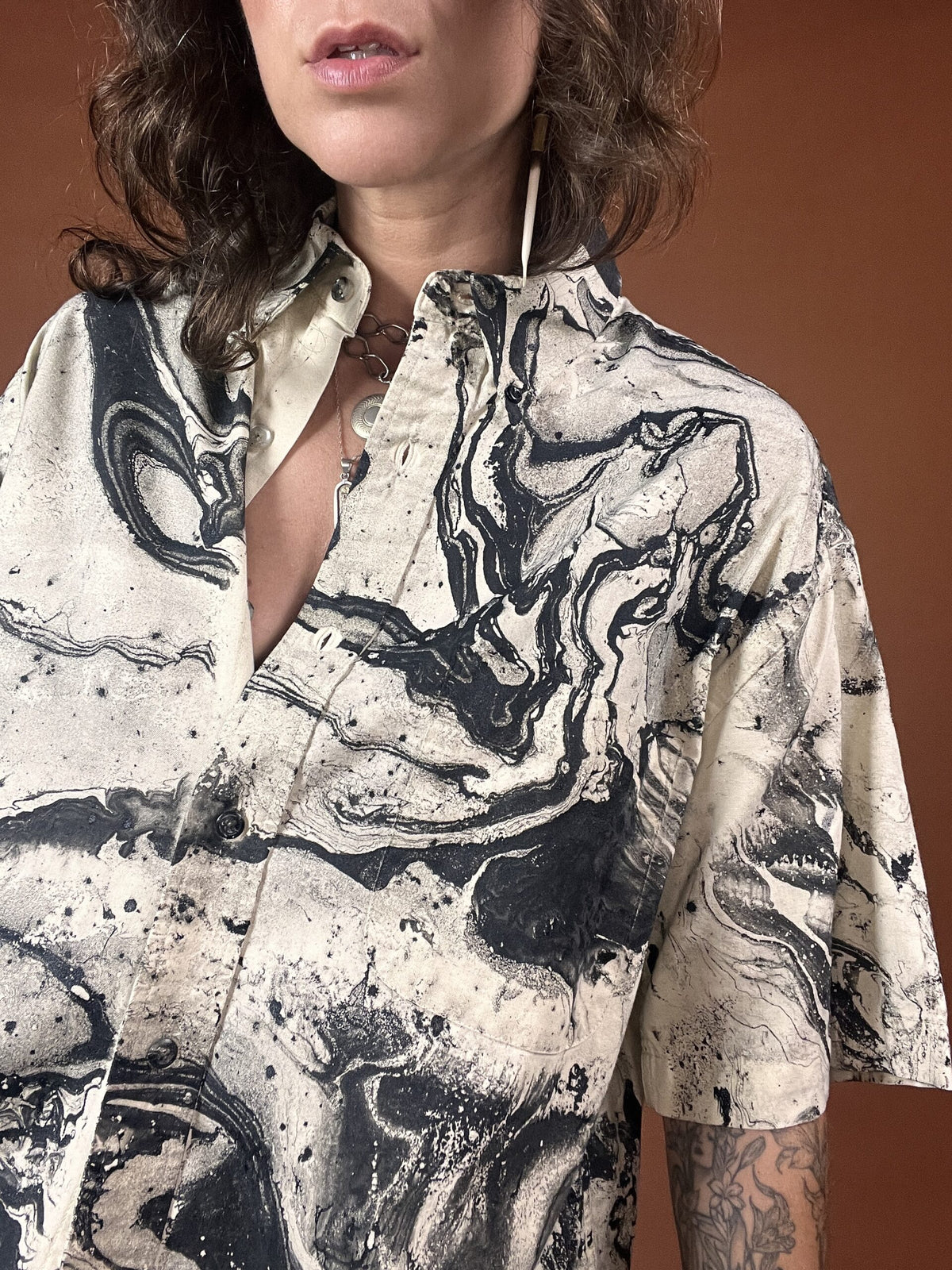 A woman wearing a black and white shirt with tattoos.