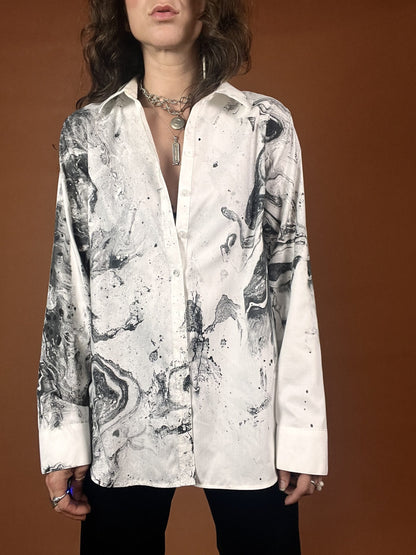 A woman wearing a white shirt with black and white paint on it.