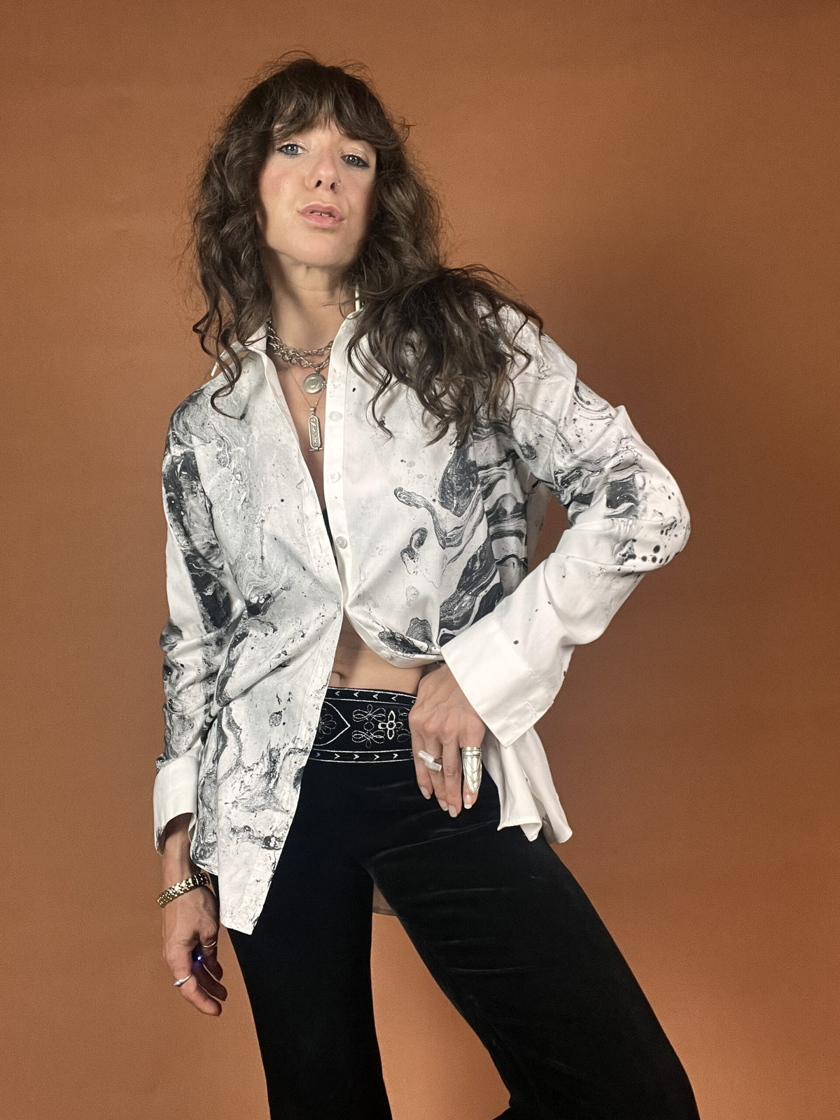 A woman in a white shirt and black pants posing.