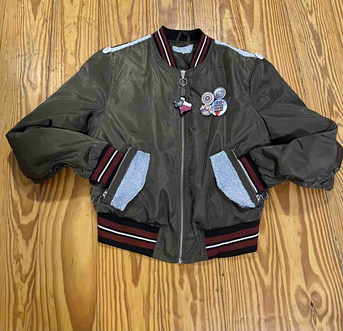 a green bomber jacket with patches on the sleeves.