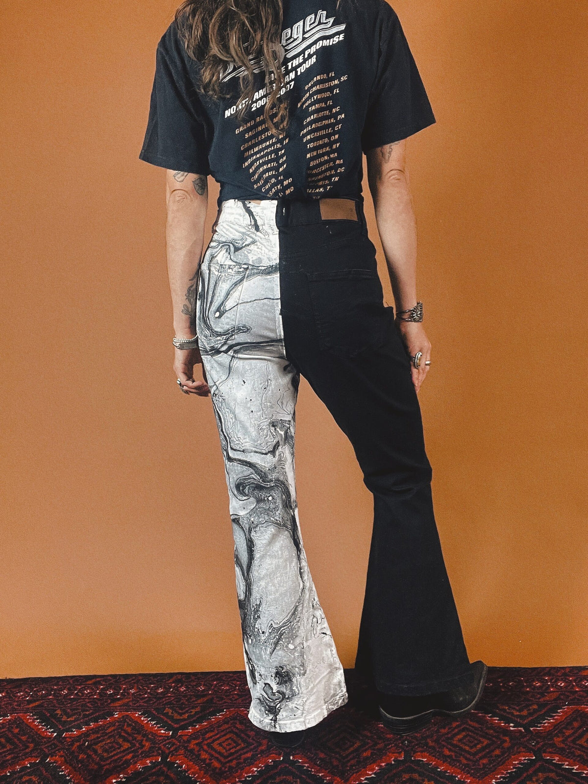 A woman wearing a black and white t - shirt and flared pants.