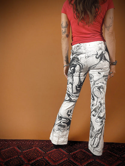 A woman in a red shirt is wearing a pair of black and white flared pants.
