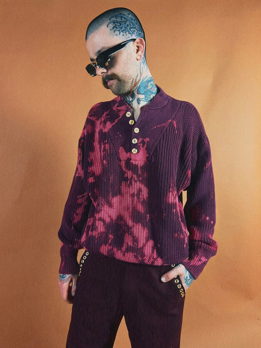 Man with tattoos wearing sunglasses and a patterned sweater.