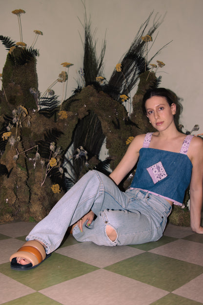 A woman sitting on the floor in an Upcycled Denim Crop Top, Vintage Purple Bandana Straps, S/M and sandals.