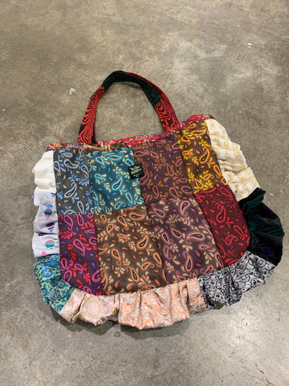 A colorful patchwork bag on a concrete floor.