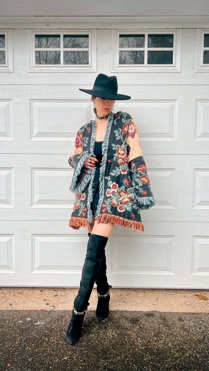 Person in a fashionable outfit with a wide-brimmed hat posing in front of a white garage door.
