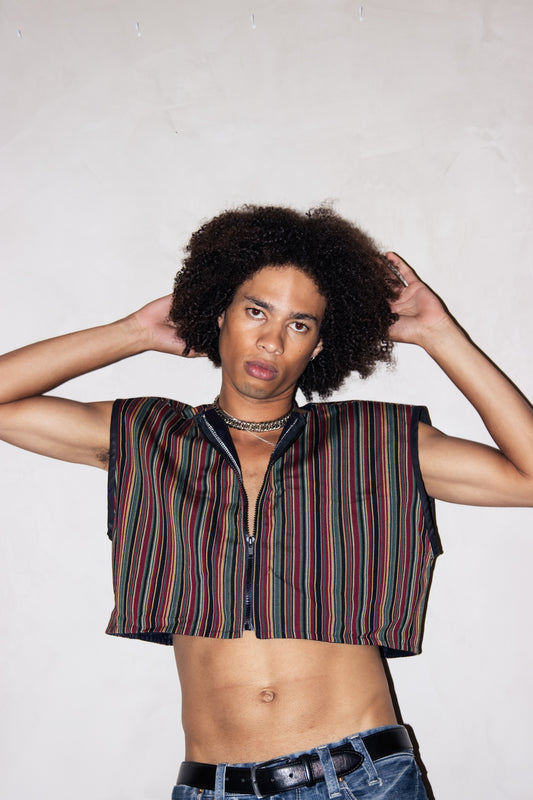 A young man in an Upcycled Sleeveless Cropped Jacket, One Size Fits Most, 1 of 1 posing with his hands on his hips.